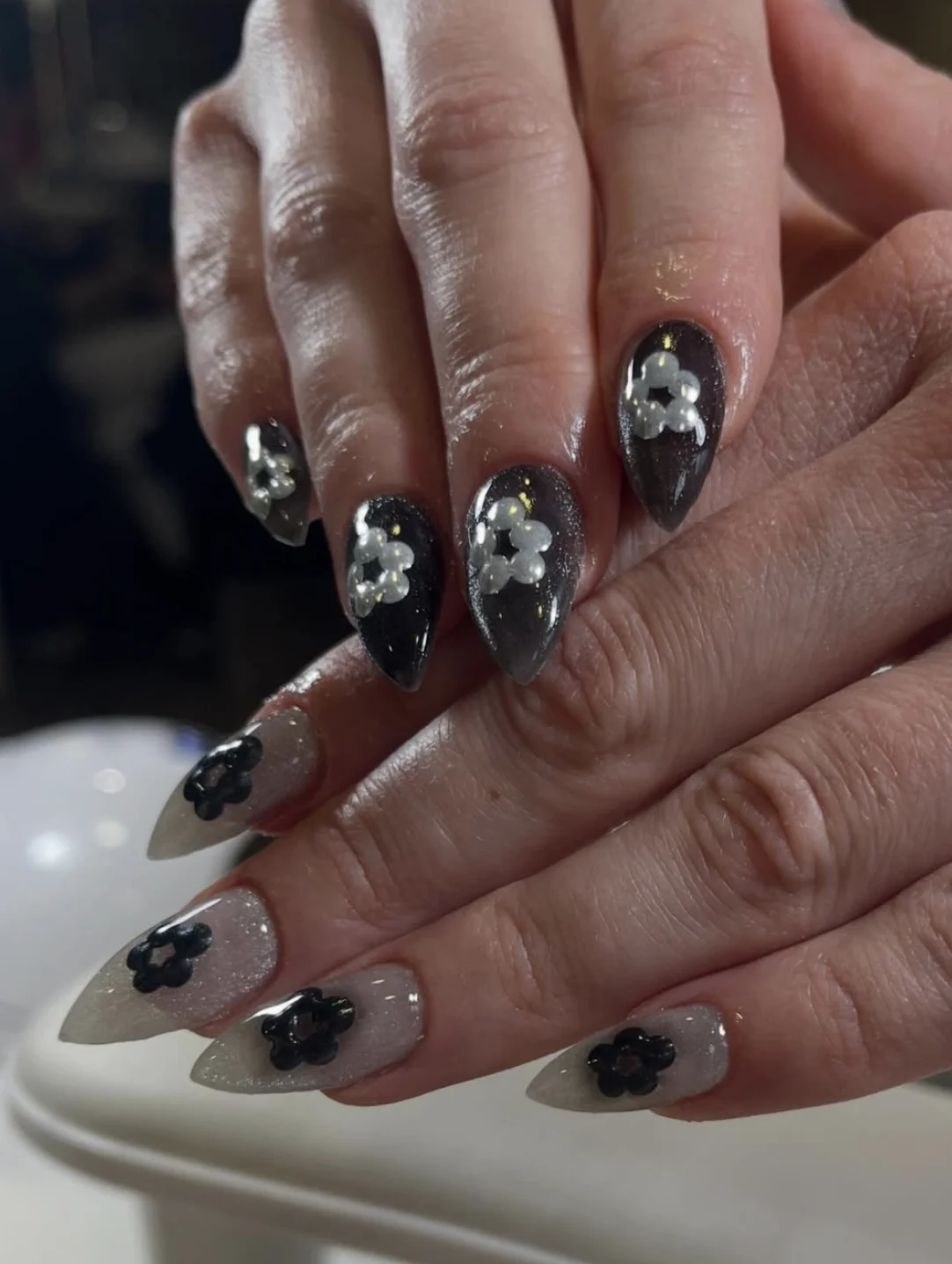 Ongles stiletto noirs et nacrés avec fleurs en perles blanches et noires