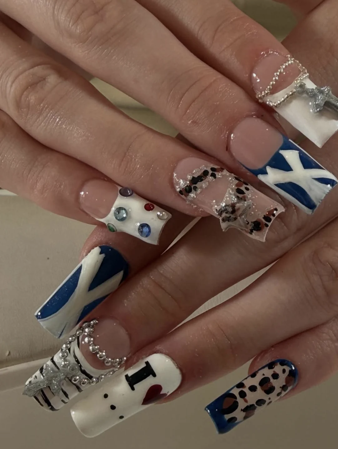 Ongles longs carrés avec drapeaux bleus, strass colorés, chaînes argentées et motif léopard